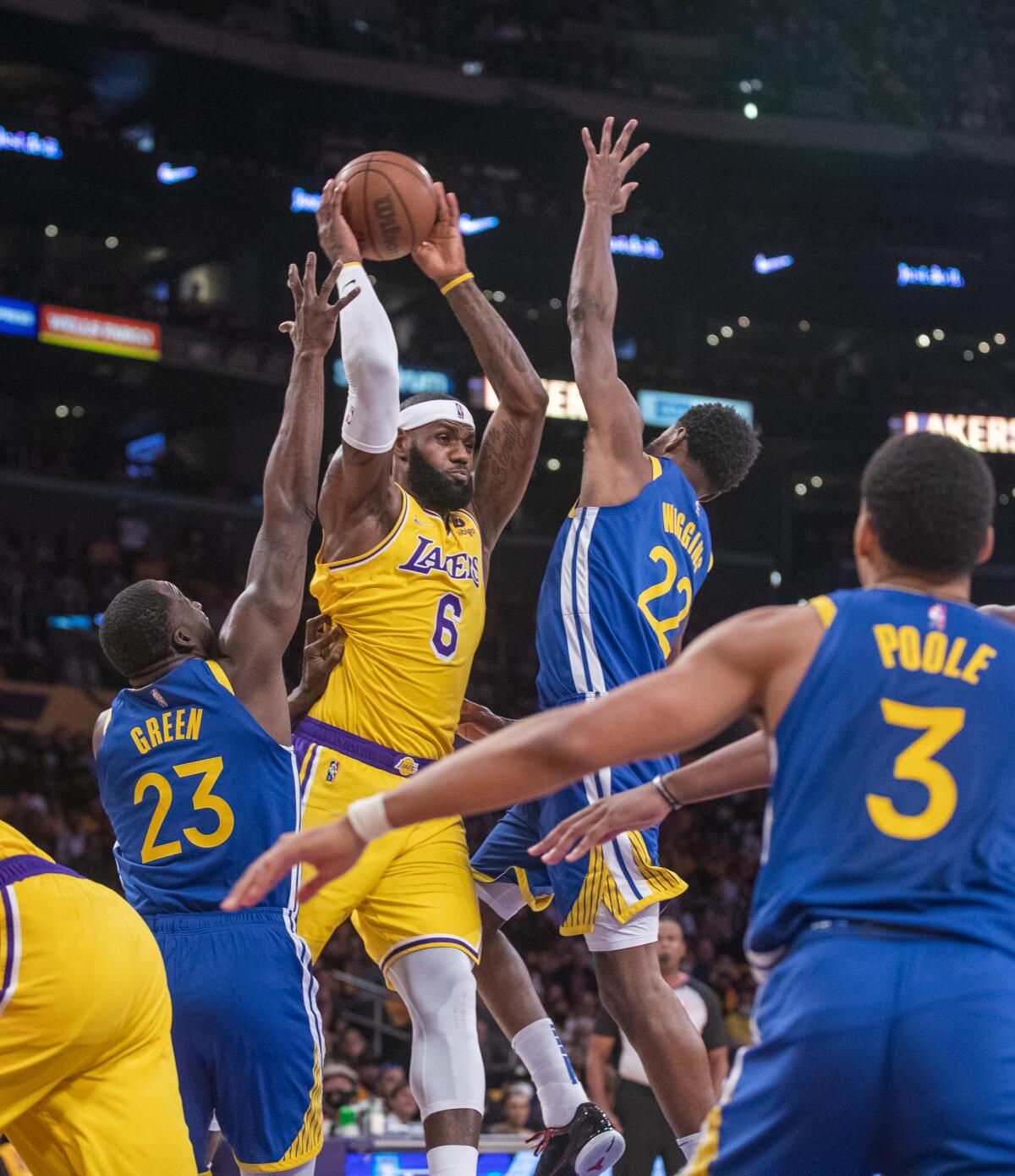 Lakers forward LeBron James tries to keep the ball away from Golden State's Draymond Green and forward Andrew Wiggins.