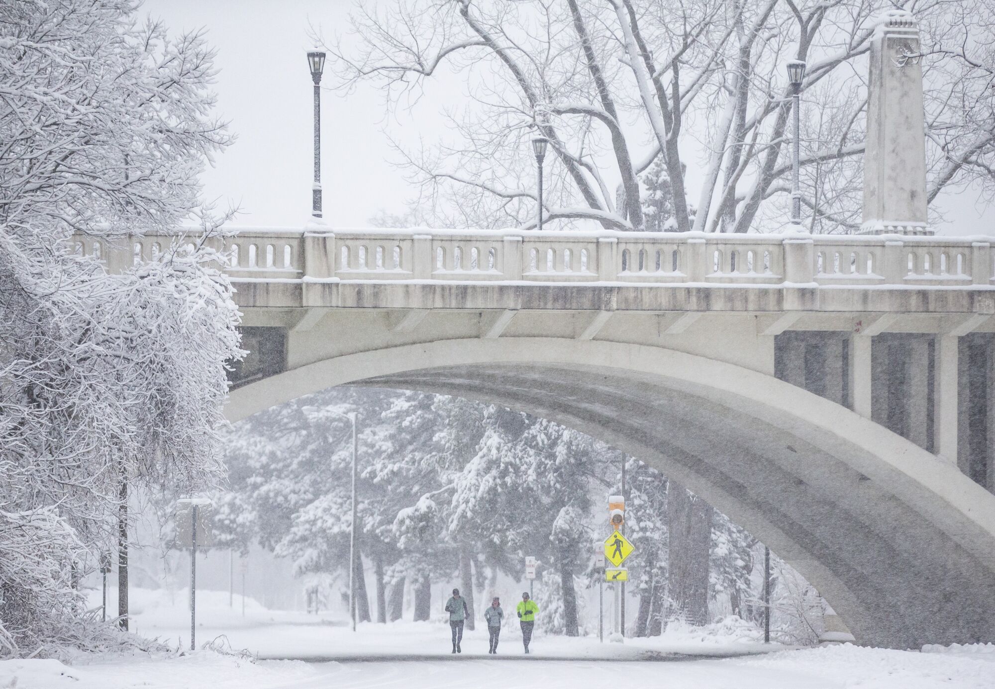 People jog under a bridge during a snowstorm