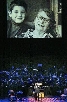 Michael Tilson Thomas stands before a contingent of the Los Angeles Philharmonic beneath a projection of an early photo of himself with his celebrated grandmother, Bessie. The San Francisco Symphony's music director is paying tribute to his grandparents at Walt Disney Concert Hall with The Thomashefskys: Music and Memories of a Life in the Yiddish Theater."