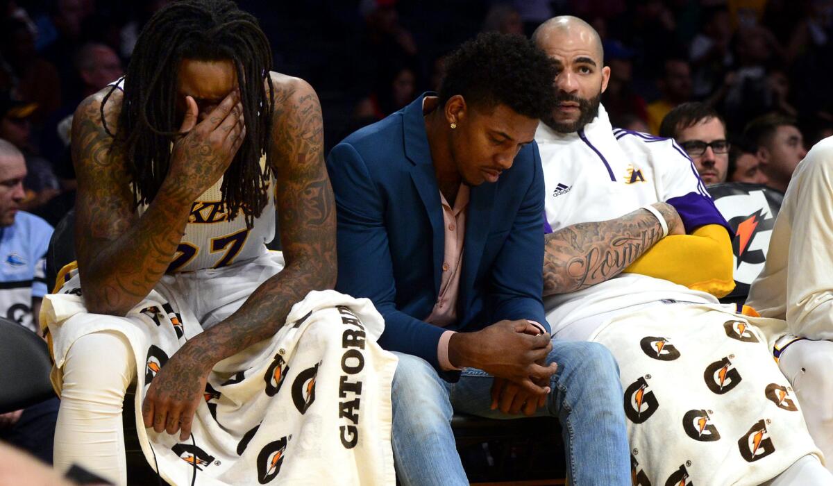 Injured guard Nick Young sits between Lakers big men Jordan Hill, left, and Carlos Boozer, late in the game against the Clippers on April 5 at Staples Center.