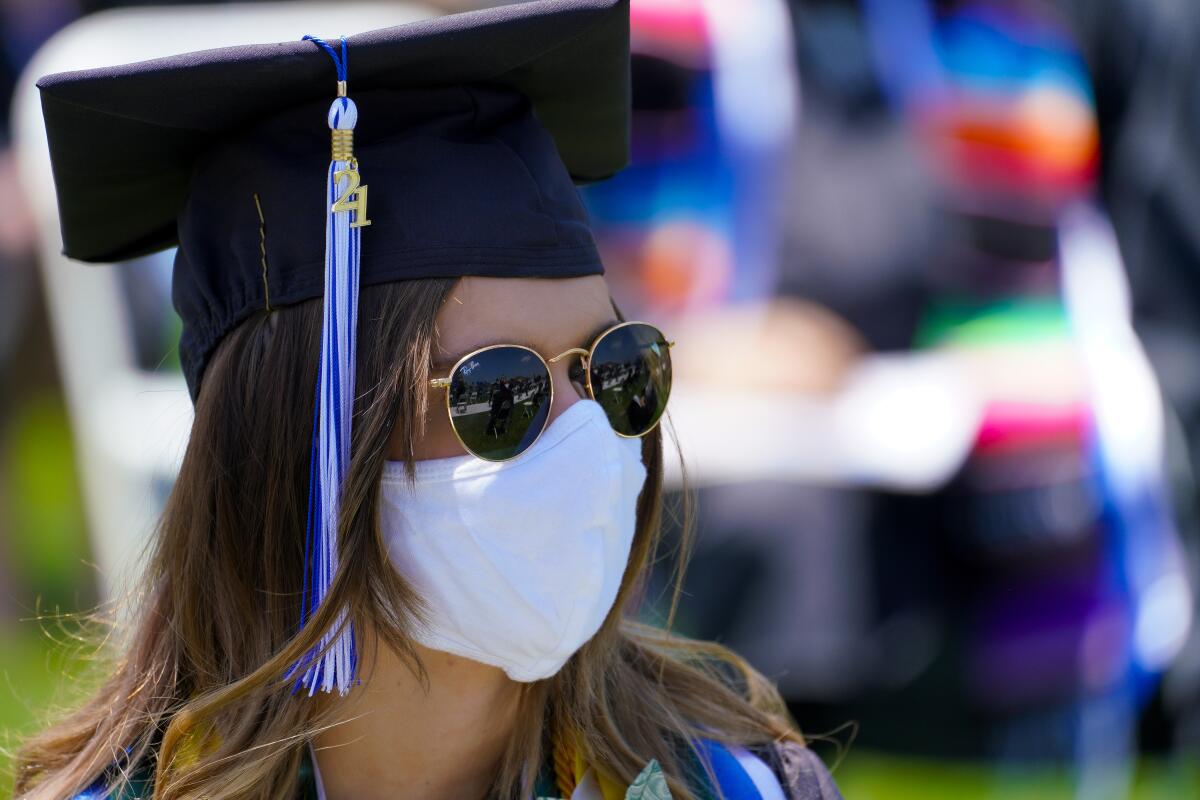 Bailey Calhoun, 23, waits at her seat for the start of graduation ceremony Saturday, wearing a mask.