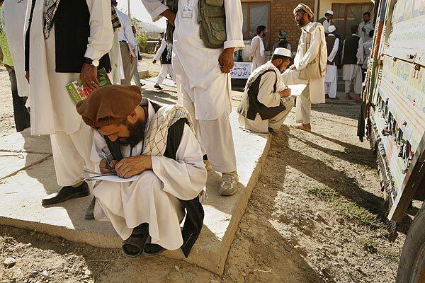 Afghans fill out paperwork at a polling station near north Kabul. The early morning turnout was light amid fears of violence by militants.