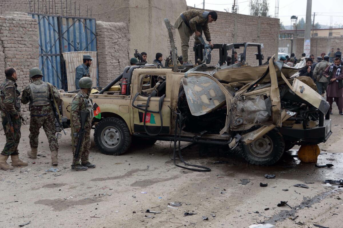 Afghan soldiers inspect a damaged army vehicle at the site of a bomb blast in Nangarhar province.
