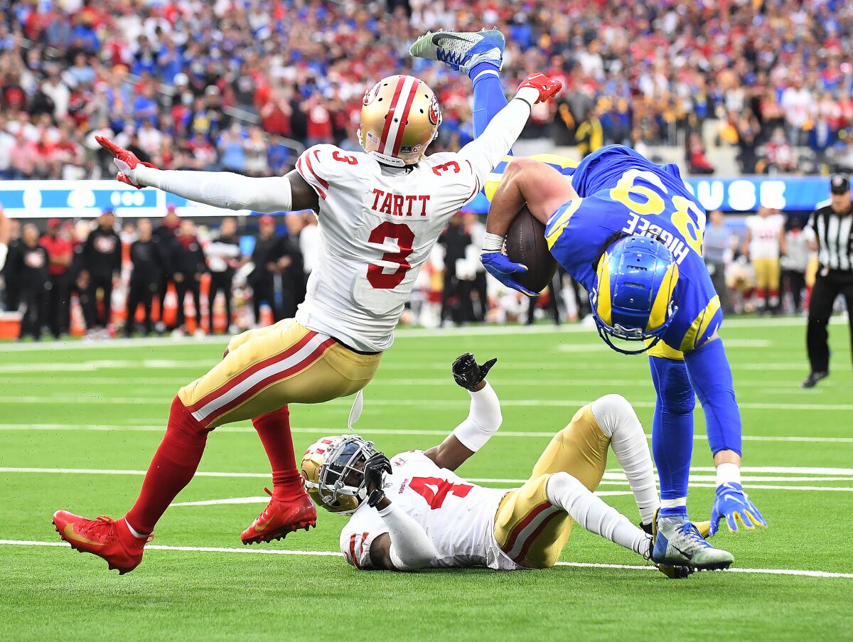 The Rams' Tyler Higbee is upended by Emmanuel Moseley and Jaquiski Tartt in the first quarter, when Higbee injured his knee.