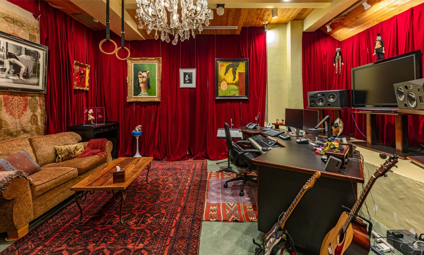 The recording studio with furniture, red draped walls, paintings, guitars and a sound equipment.