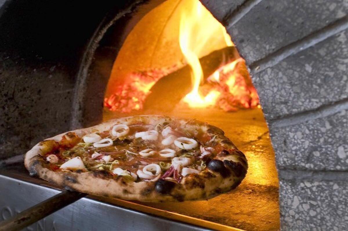 Pizza alla puttanesca comes out of an 850-degree wood oven at Cotogna.