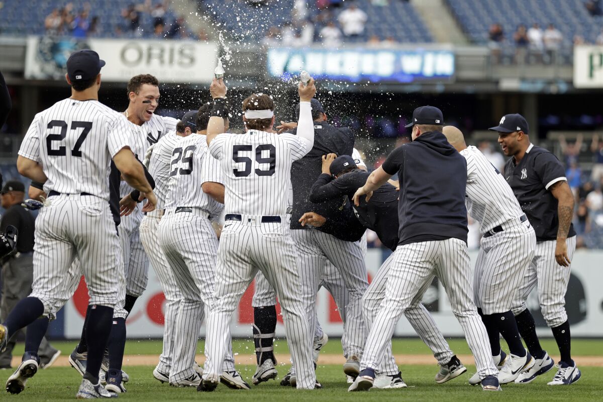 Teammates mob New York Yankees' Gary Sanchez after he hit a walkoff single against the Minnesota Twins during the 10th inning of a baseball game on Monday, Sept. 13, 2021, in New York. (AP Photo/Adam Hunger)