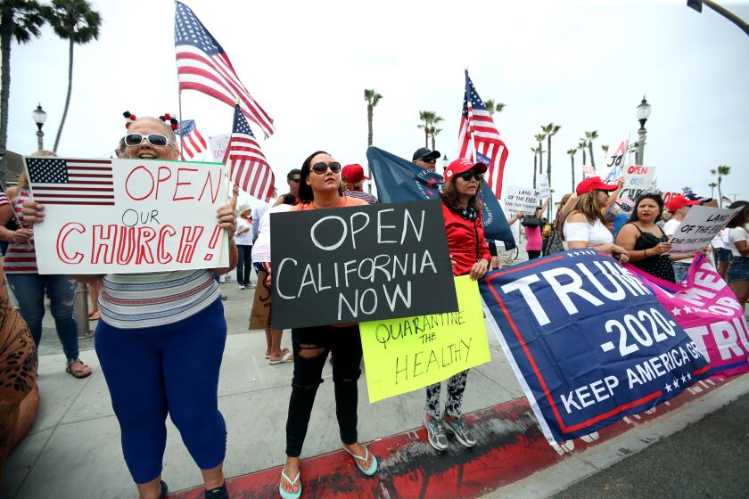 Protesters hold signs for opening churches and the state of California during the protest at Pier Plaza in Huntington Beach on Saturday.