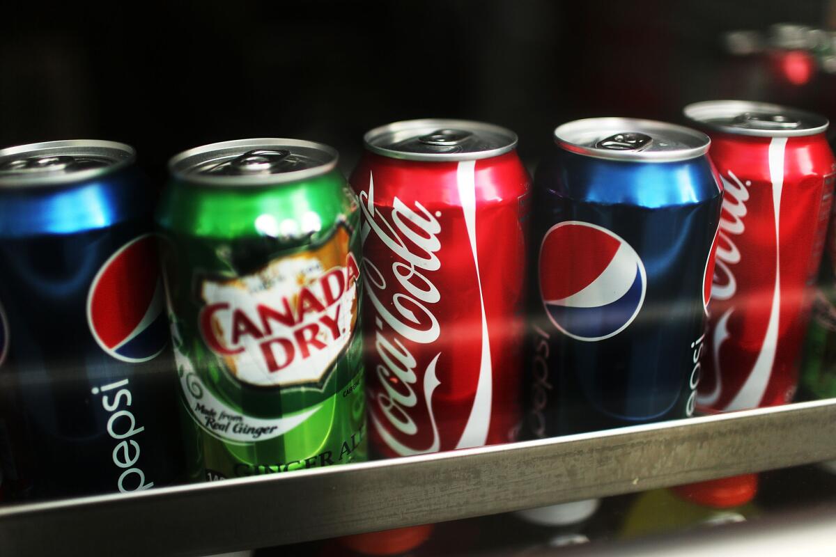 Cans of soda are displayed on a store shelf. The state Senate on Thursday supported a bill requiring health warning labels on the sugary drinks.