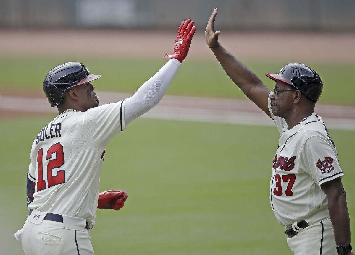 The Braves' Jorge Soler is congratulated by third base coach Ron Washington 