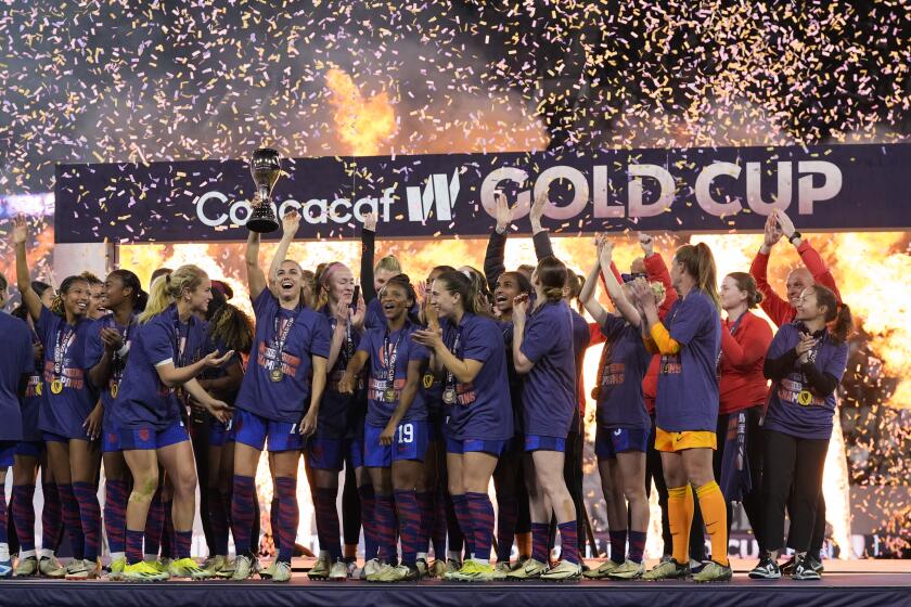 American Alex Morgan holds the trophy beside teammates after they beat Brazil in the CONCACAF Gold Cup women's final