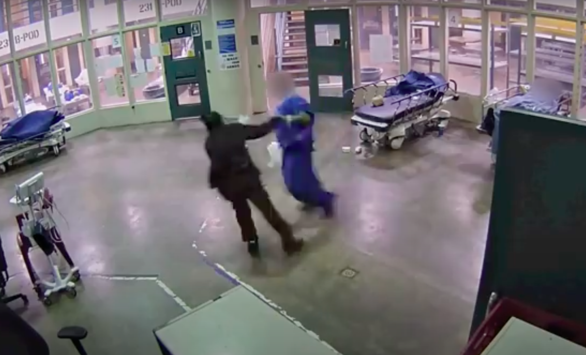 Two people scuffle in the middle of a large empty room  