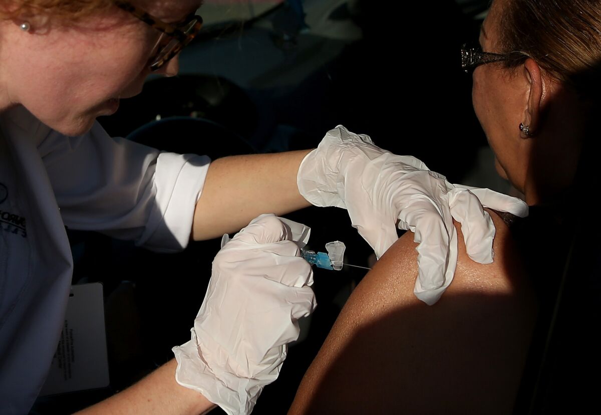 A flu vaccine is administered during a drive-through flu shot clinic at Doctors Medical Center in San Pablo, Calif., in November 2014.