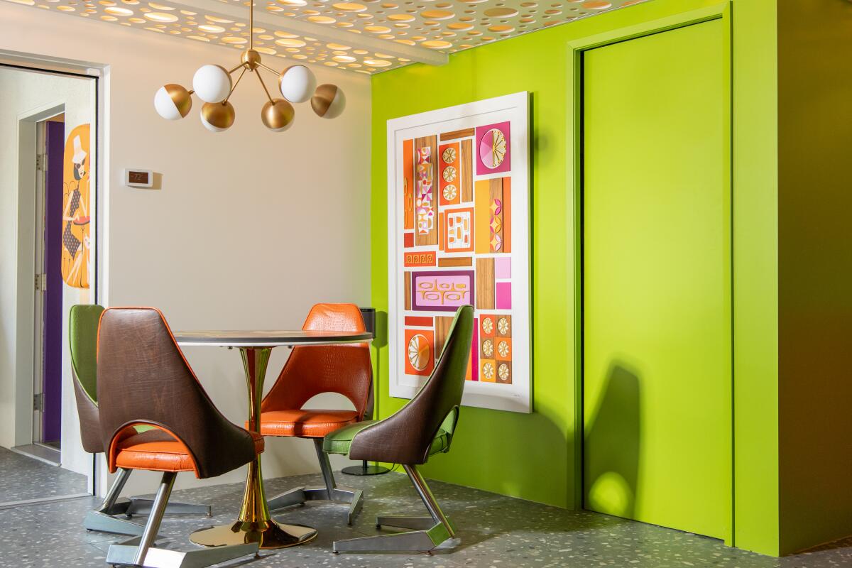 A nook in a Midcentury Modern home features bright lime green walls and a dining set with orange accents.