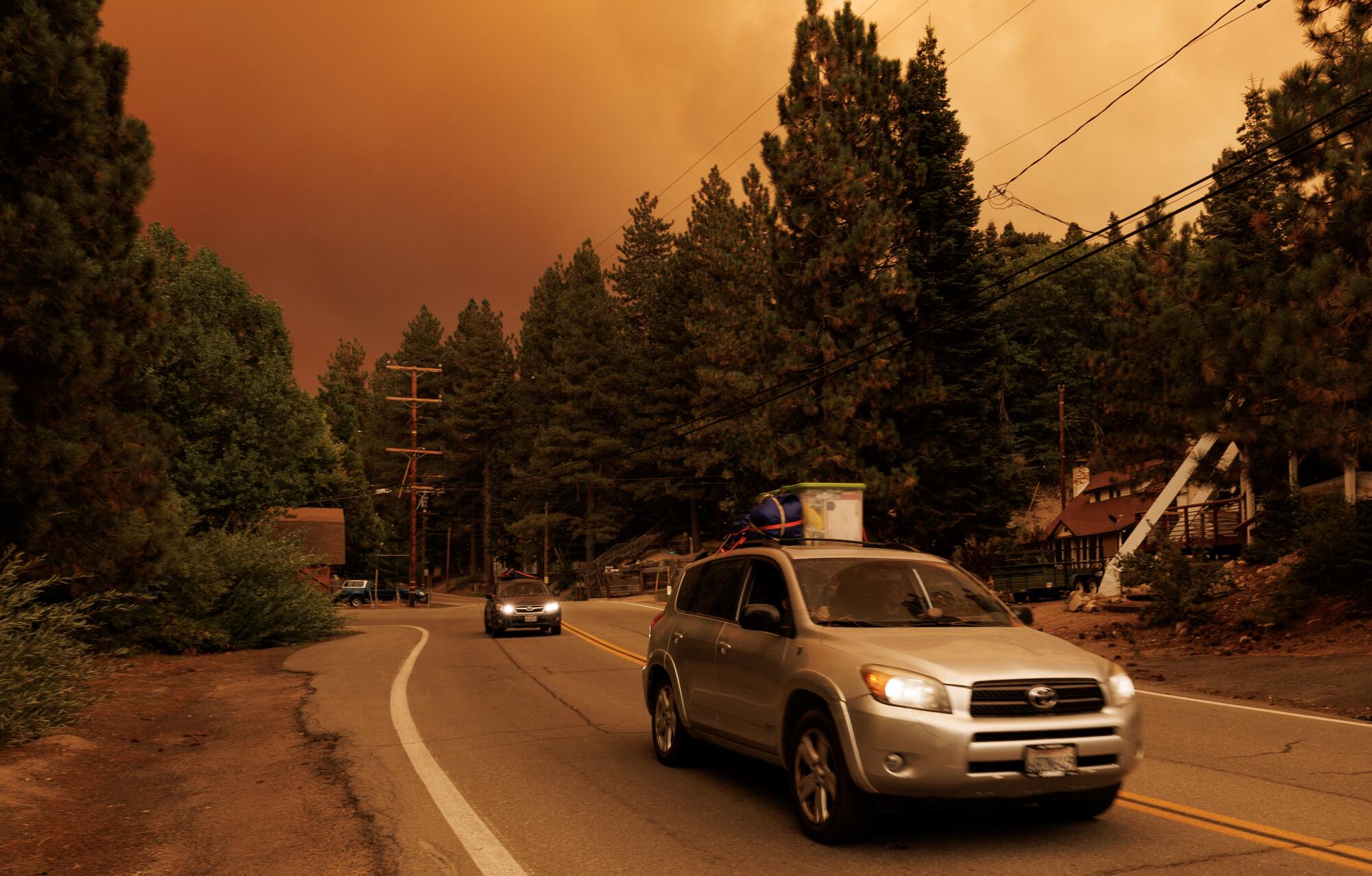 Packed cars drive away from a cloud of smoke.