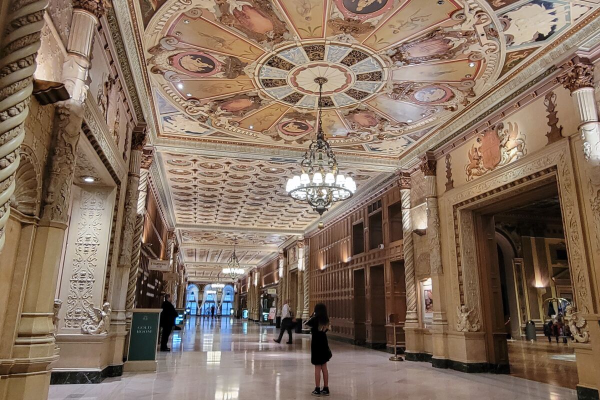A towering galleria with mosaics radiating above circular chandeliers.