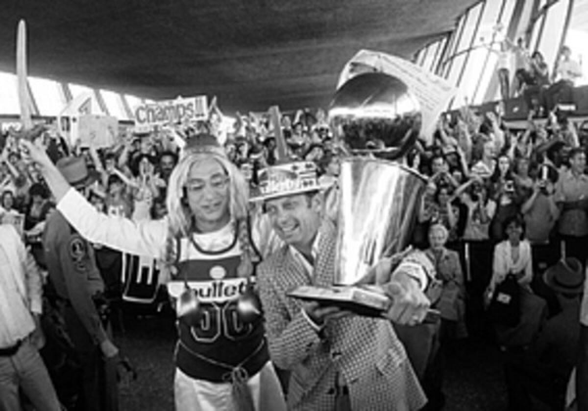 Abe Pollin holds up the NBA Championship trophy as what were then the Washington Bullets return to Dulles Airport after defeating the Seattle SuperSonics. Pollin renamed his team in 1997 because of the violent connotation of the word "bullets," particularly in a city associated with crime.