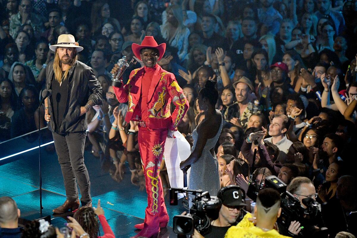 Lil Nas X in a custom Union Western Clothing suit, Gladys Tamez Millinery hat and pskaufman boots, accepting one of his MTV Video Music Awards with Billy Ray Cyrus in August 2019. 