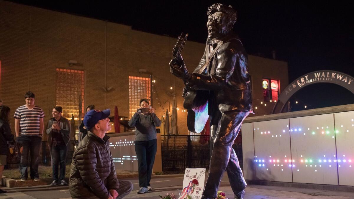 Passersby pay tribute to Chuck Berry, stopping at a statue of the rock 'n' roll pioneer in University City, Mo., on Saturday, the day he died at age 90 at his home in a St. Louis suburb.