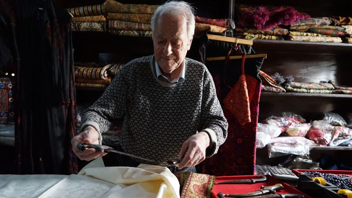 Syrian textile merchant Joseph Havera unfolds damask tablecloths in Damascus. He fears the prospect of greater U.S. intervention in Syria.