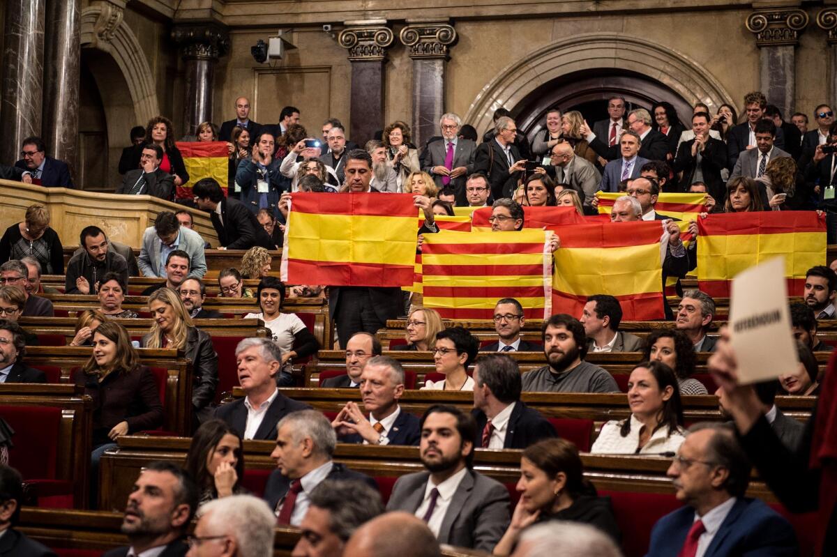 Spanish and Catalan flags are held up at the end of the Catalan parliamentary session Monday in Barcelona, Spain. The regional parliament passed a motion declaring the start of an 18-month process to break away from Spain.