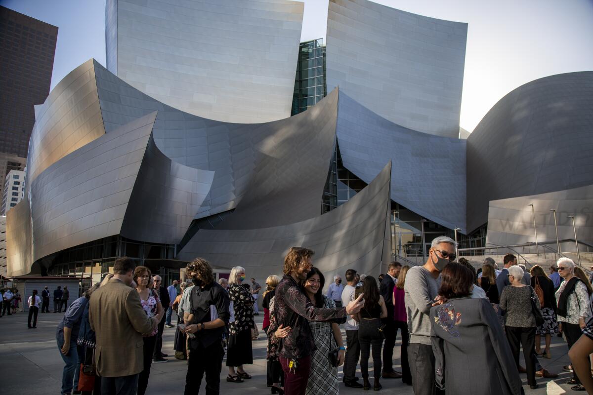 Masked people wait outside Walt Disney Concert Hall