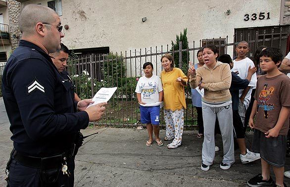 Drew Street resident Patricia Gomez scolds police officers because her children were frightened by the early morning raid on her building targeting reputed gang members. The Avenues gang's Drew Street clique has kept control over the neighborhood despite a series of efforts by federal and local law enforcement agencies over the years, officials said.
