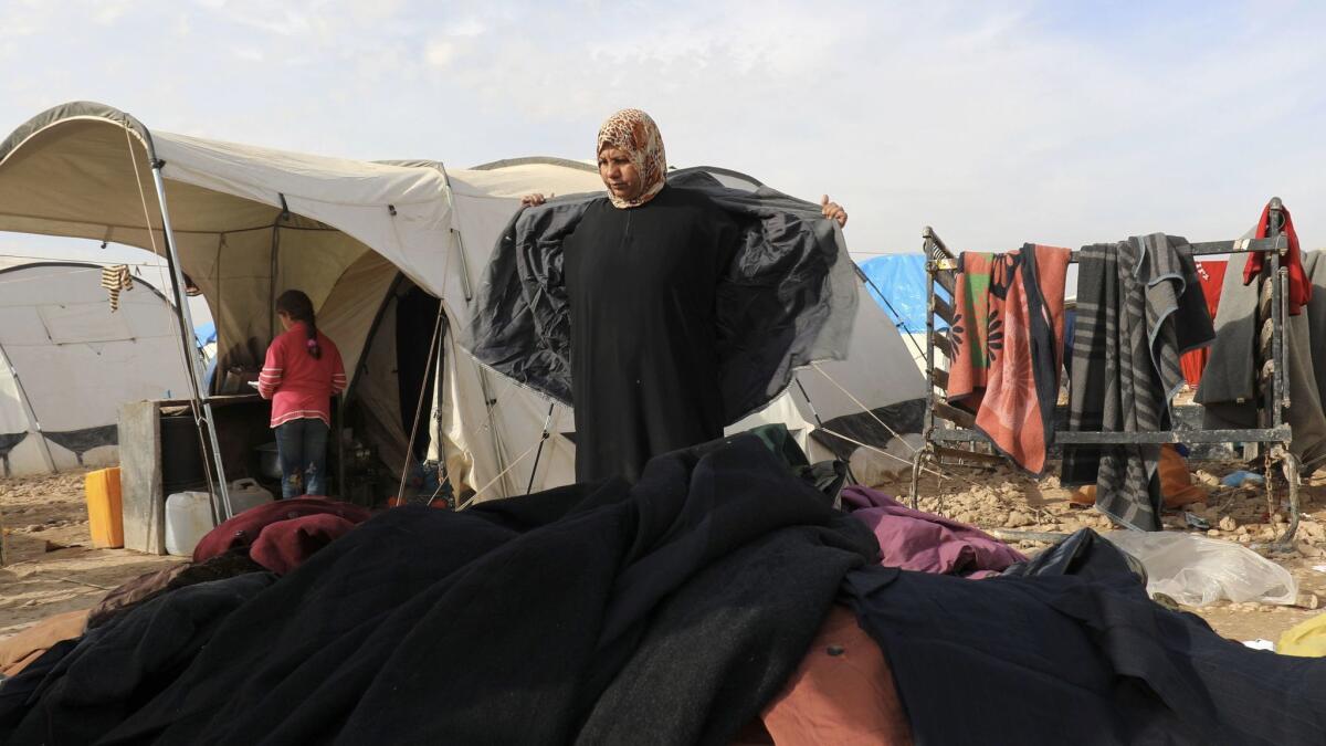 A displaced Syrian woman, who was forced to leave her hometown in the war against Islamic State, tries on donated clothes at the Ain Issa camp.