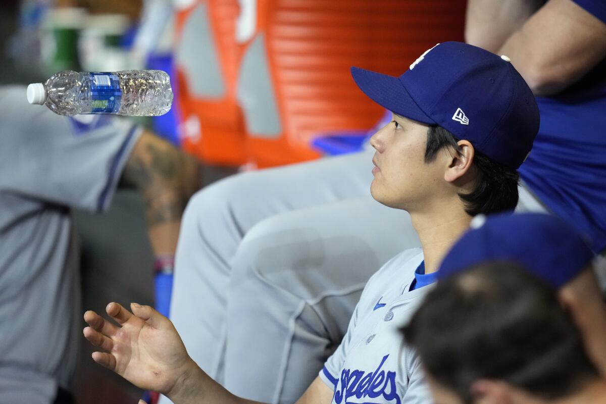 Shohei Ohtani flips a water bottle in the air while sitting on the bench during Wednesday's game against the Diamondbacks.