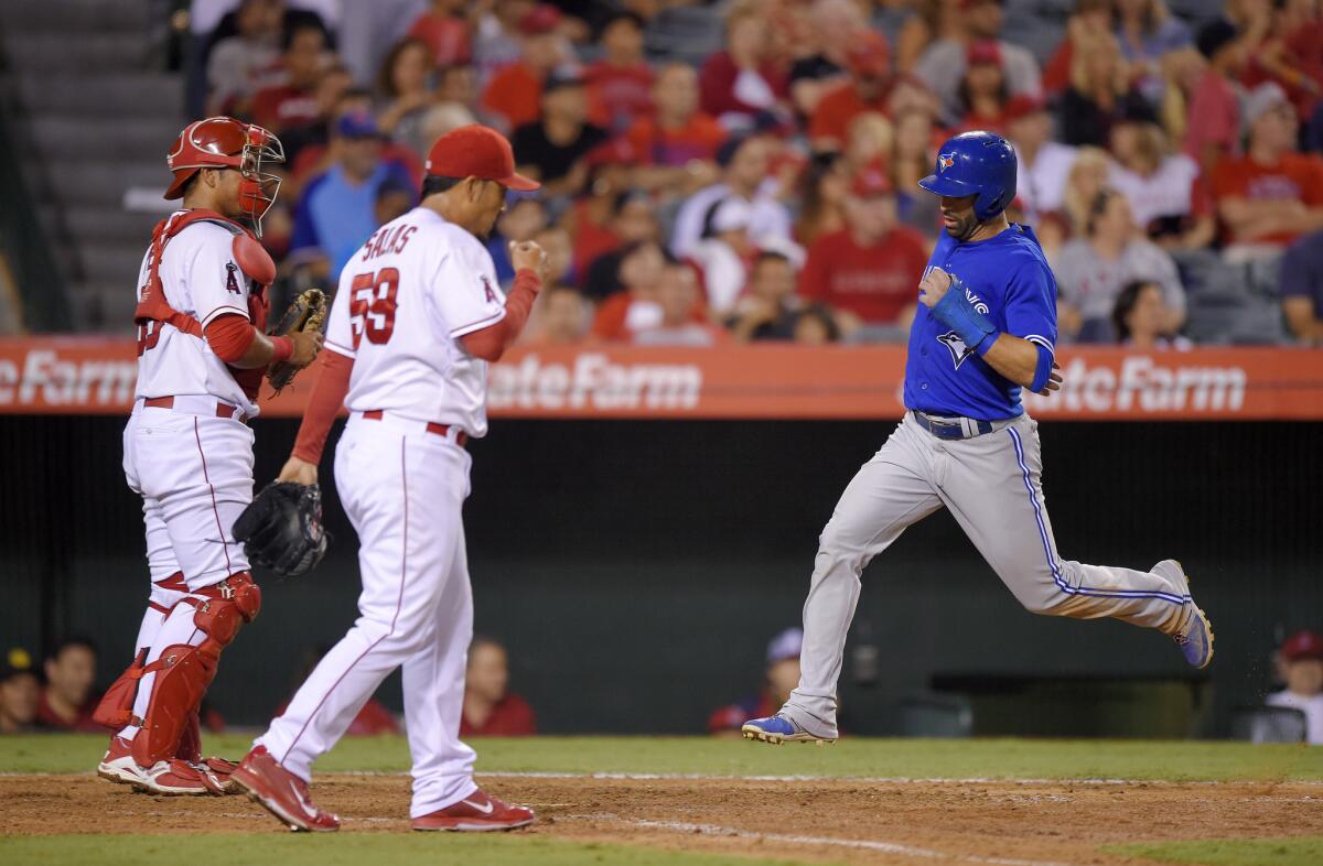 Toronto's Jose Bautista, right, scores past Angels catcher Carlos Perez, left, and relief pitcher Fernando Salas during the eighth inning on Saturday night.