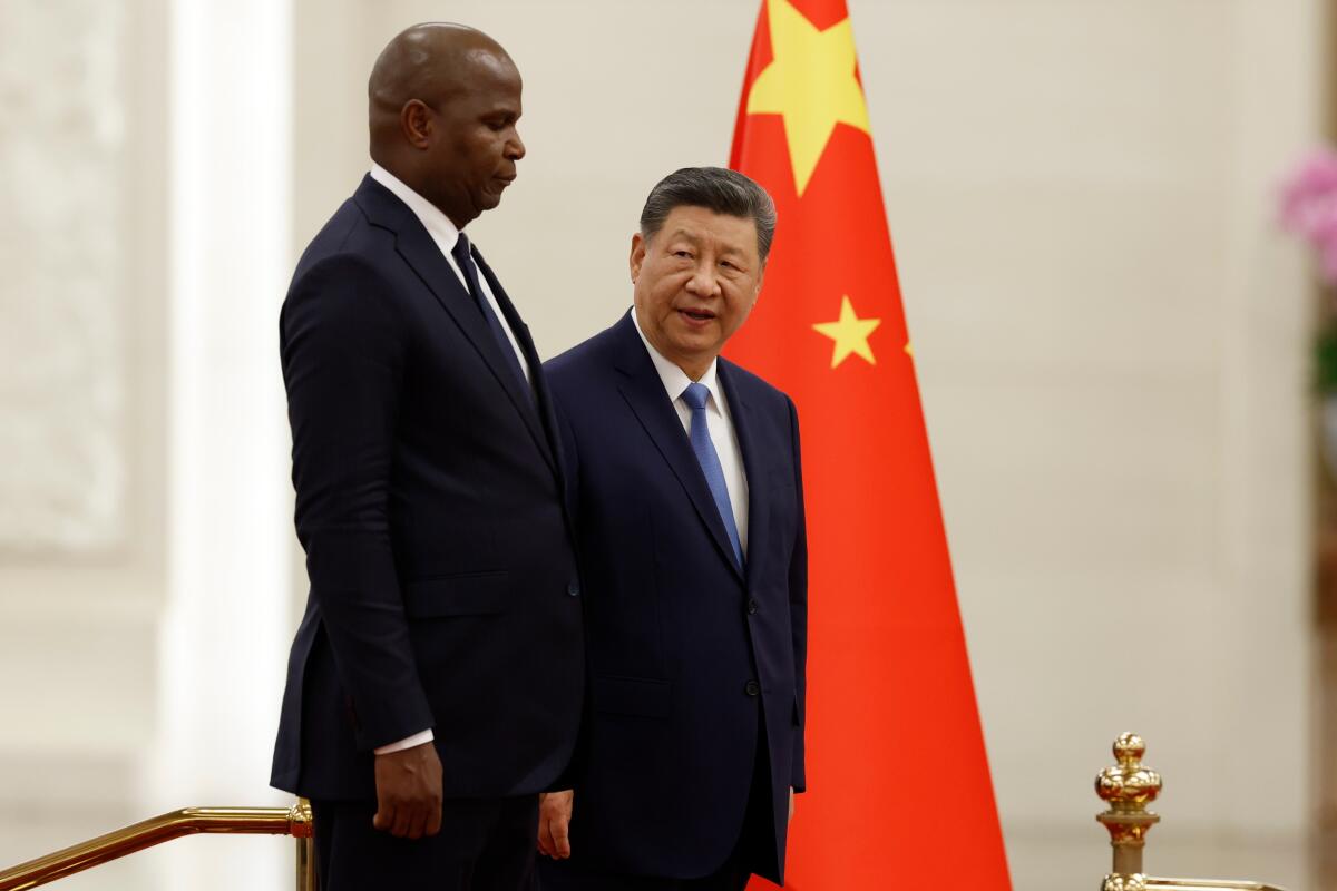 中国の習近平国家主席とモザンビークのダニエル・チャポ大統領が中国国旗の前で並んで立っている。