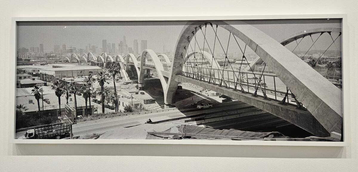 A black and white photograph of a bridge with 10 arches. 