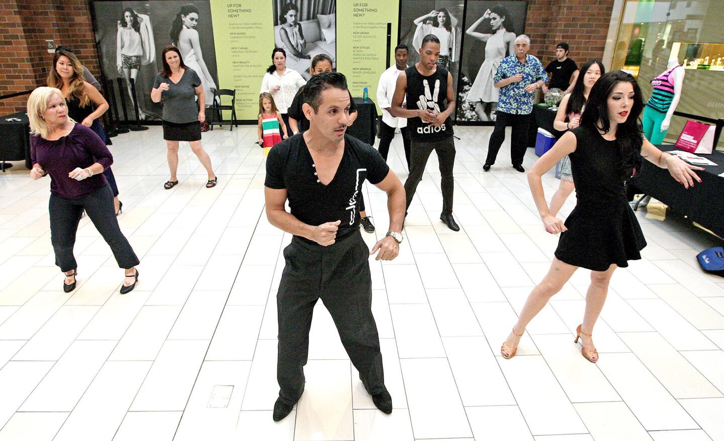 Sergio Leal of Latin Dance Pro, center, leads a Latin dance class with teacher Isabella Grosso at the Glendale Galleria on Tuesday, July 29, 2014. The classes will continue every Tuesday for the next eight weeks, ending with a live band performance.