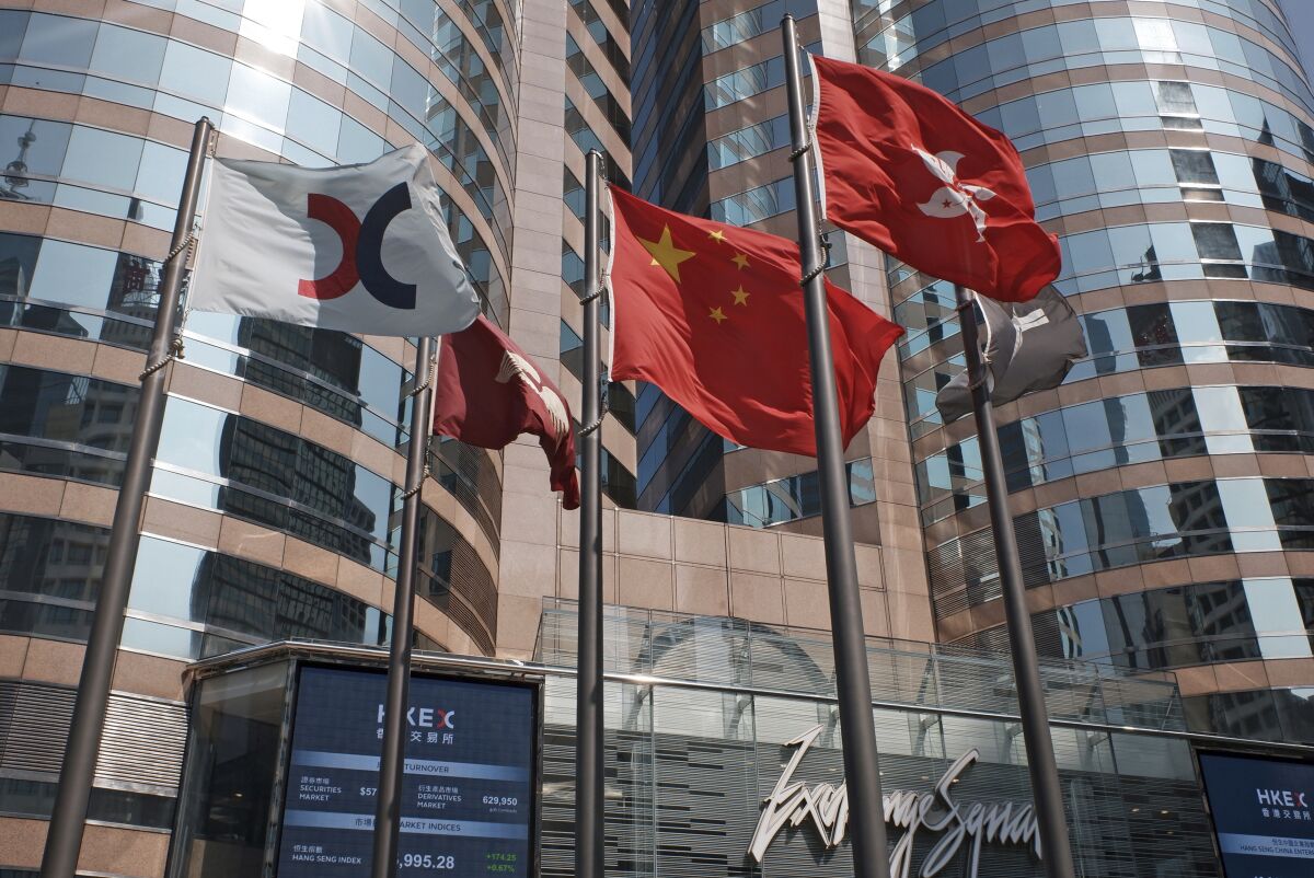 FILE - In this Oct. 9, 2019, file photo, flags are raised outside the Hong Kong Exchange Square building in Central of Hong Kong. The Hong Kong Stock Exchange said it was hit by technical problems Thursday as a wave of brief internet outages appeared to hit dozens of financial institutions, airlines and other companies across the globe. (AP Photo/Kin Cheung, File)