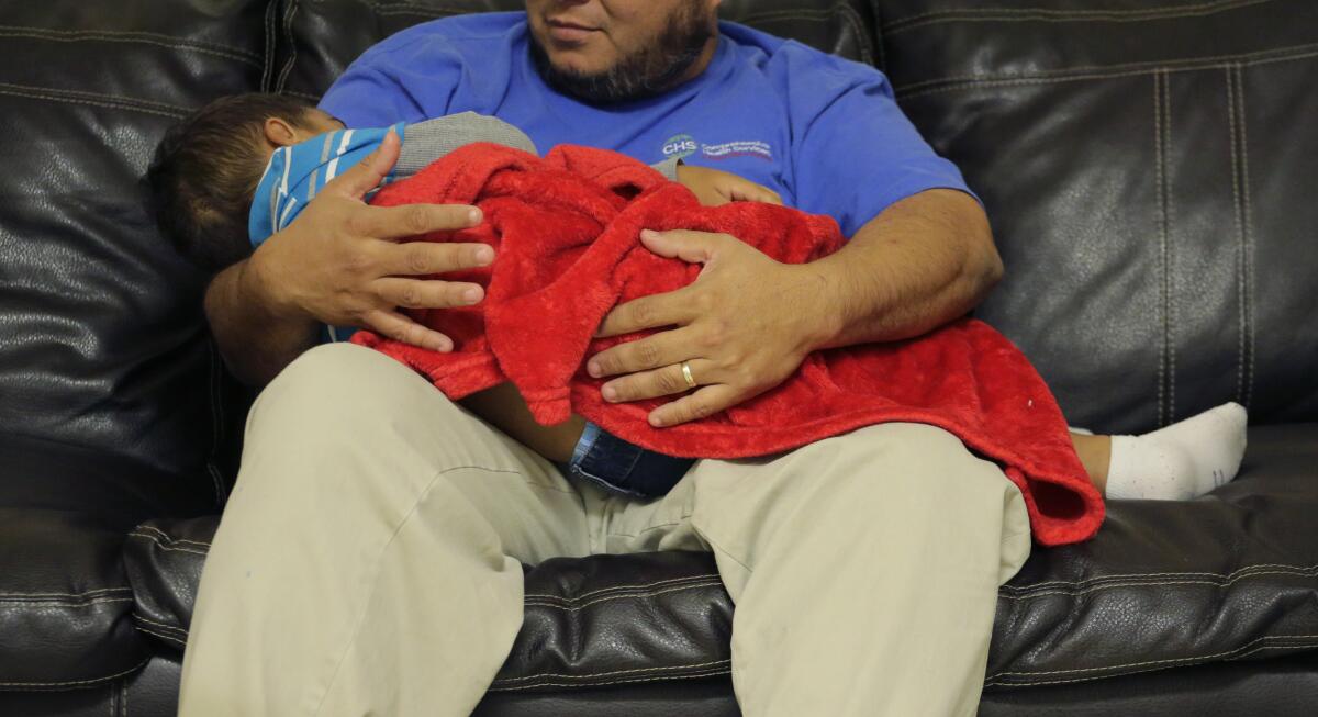 A caregiver holds a migrant toddler