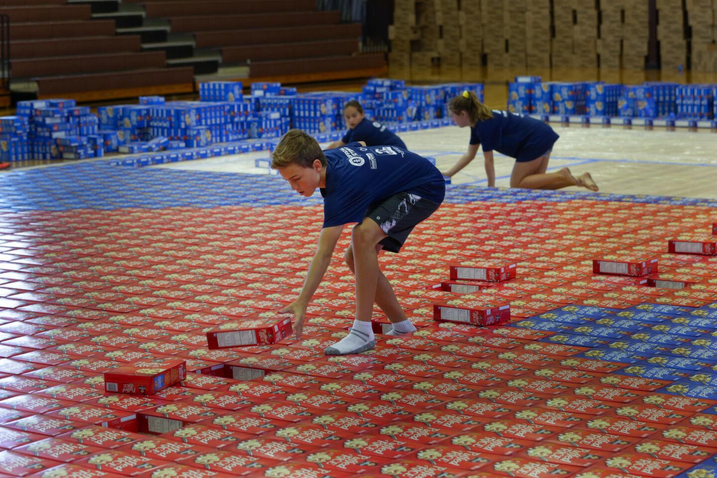 Cade Dethloff maneuvers in the middle of the cardboard mosaic as he places red cereal boxes in the shape of a heart.
