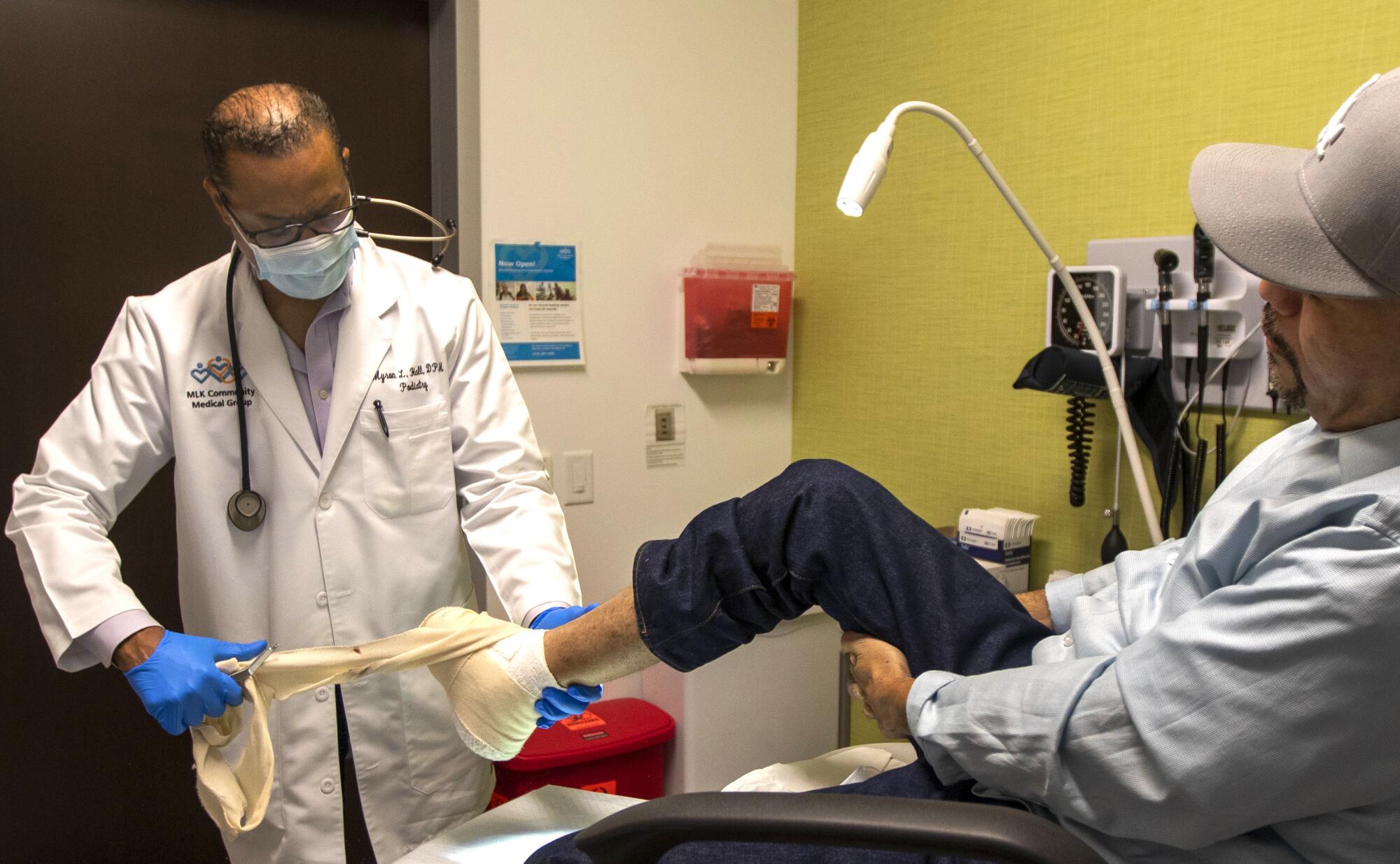 Dr. Myron Hall, left, is removing the bandages on Tony Zamora's foot.