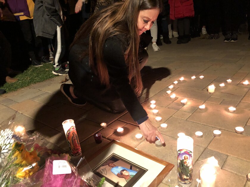 A woman relights a candle in honor of Kobe Bryant at Newport Ridge Community Park in Newport Beach during a vigil Sunday night for the former Lakers star, who died in a helicopter crash earlier in the day.