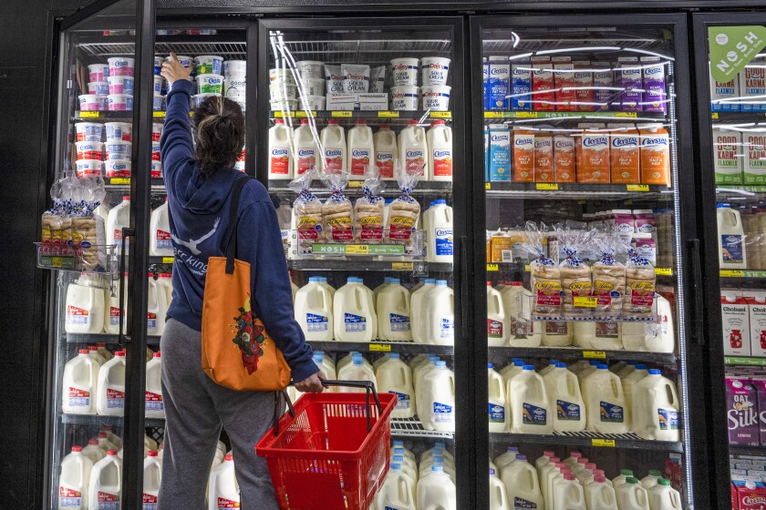 A shopper reaches for cottage cheese inside a grocery store.