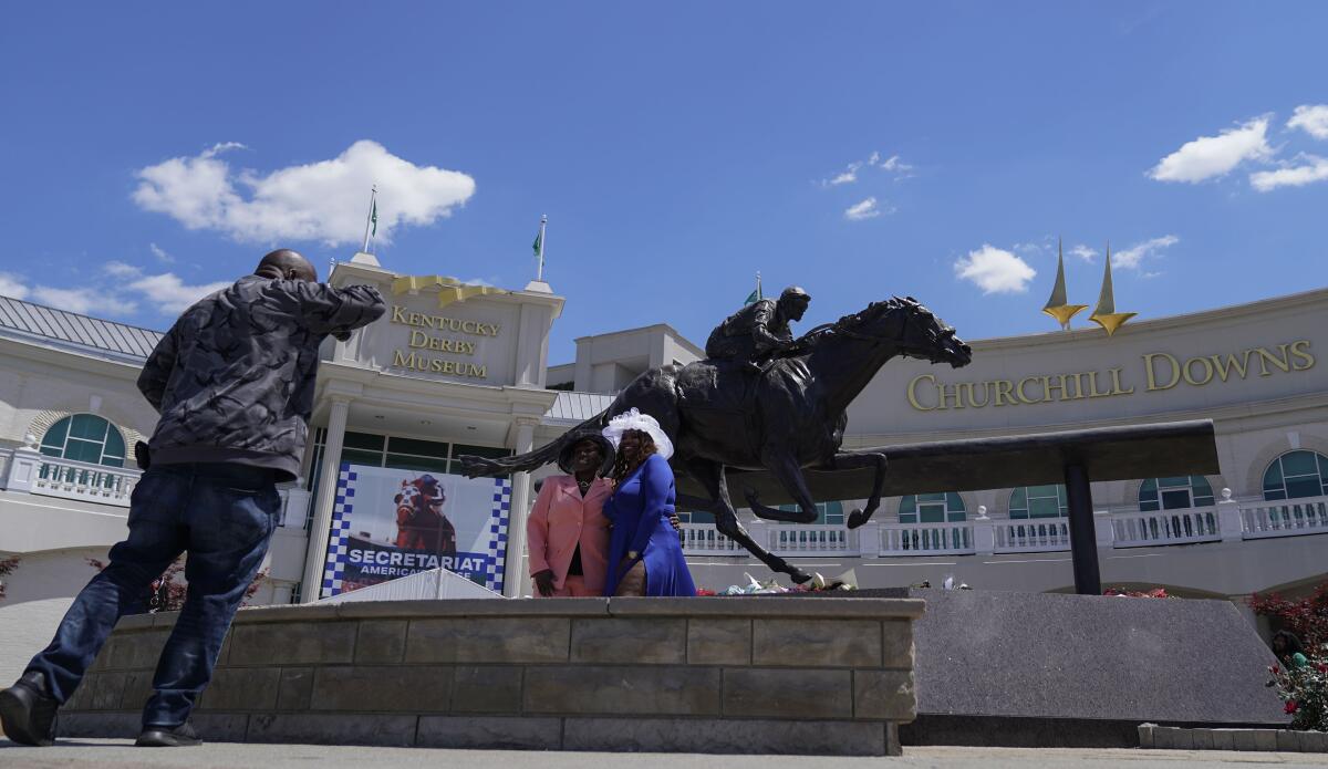 Race fans take photos in front of a statue of Barbaro at Churchill Downs