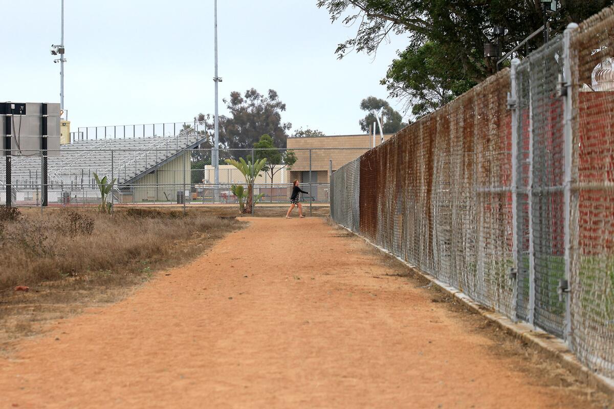 Looking toward Jim Scott Stadium, a woman uses an unauthorized trail as she makes her way from Fairview Park onto Parsons Field.