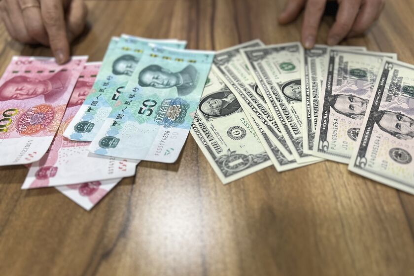 Paek H.O, who defected from the northeastern North Korean town of Musan in 2018, speaks in front of U.S. dollar and Chinese yuan notes during an interview in Seoul, South Korea, on May 3, 2023. North Korea has tolerated the widespread use of more stable foreign currencies like U.S. dollars and Chinese yuan since a bungled revaluation of the won in 2009 triggered runaway inflation and public unrest. Paek said she used the yuan to buy expensive goods and the won for cheap items such as sodas, vegetables and bread sold at markets. (AP Photo/Hyung-jin Kim)