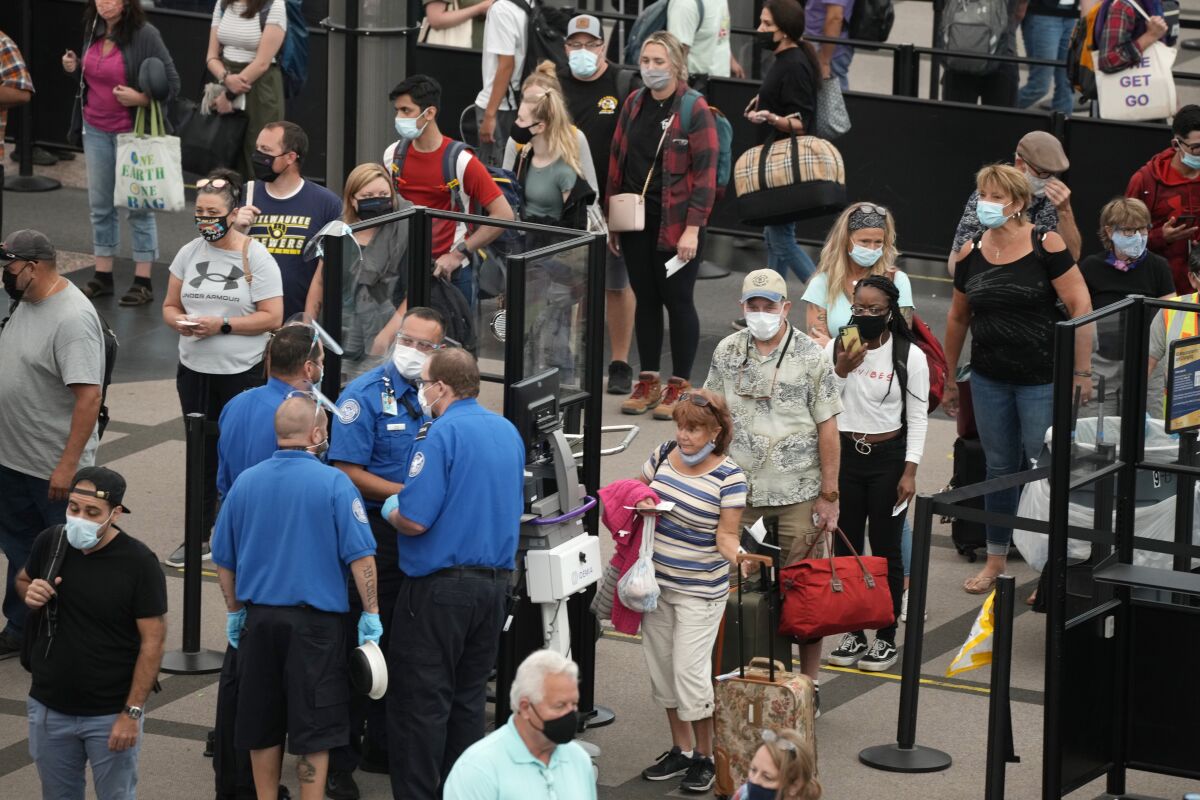 Travelers wear face coverings in the line for the south north security checkpoint in the main terminal of Denver International Airport Tuesday, Aug. 24, 2021, in Denver. Two months after the Sept. 11, 2001 attacks, President George W. Bush signed legislation creating the Transportation Security Administration, a force of federal airport screeners that replaced the private companies that airlines were hiring to handle security. (AP Photo/David Zalubowski)