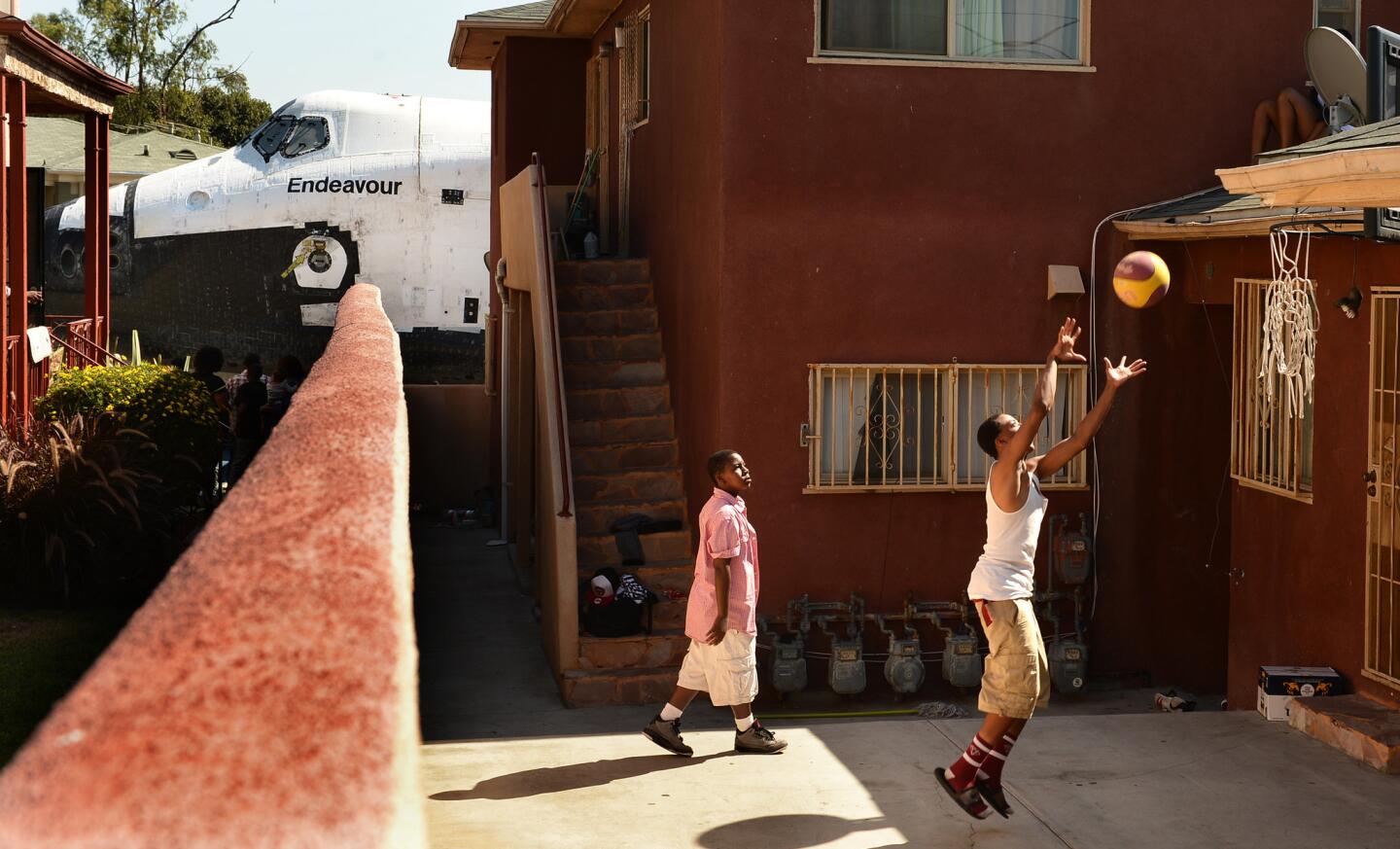 Traymond Harris, left, and Ryan Hudge play basketball as the space shuttle Endeavour passes by on Crenshaw Avenue in Inglewood.