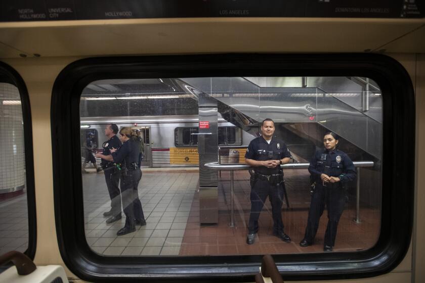 LOS ANGELES, CALIF. -- THURSDAY, MARCH 26, 2020: LAPD officers stand guard inside the 7th St/Metro Center subway station in Los Angeles, Calif., on March 26, 2020. The coronavirus pandemic is causing ridership on LA Metro trains and busses to plummet. (Brian van der Brug / Los Angeles Times)