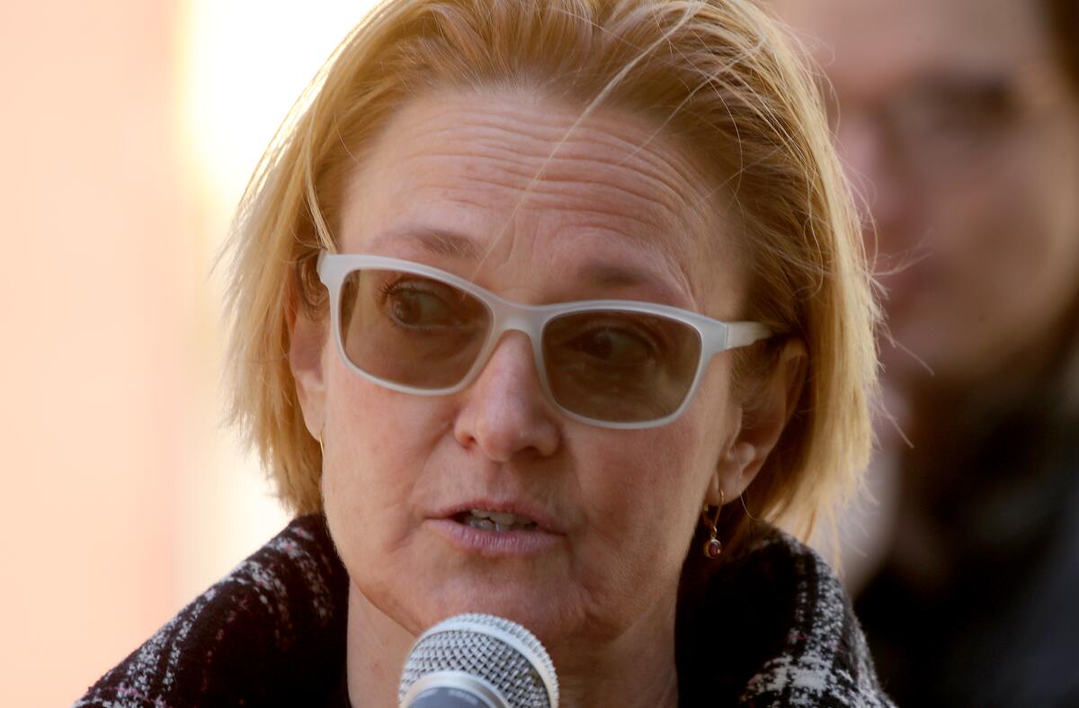 Closeup of a woman in dark glasses speaking into a microphone.