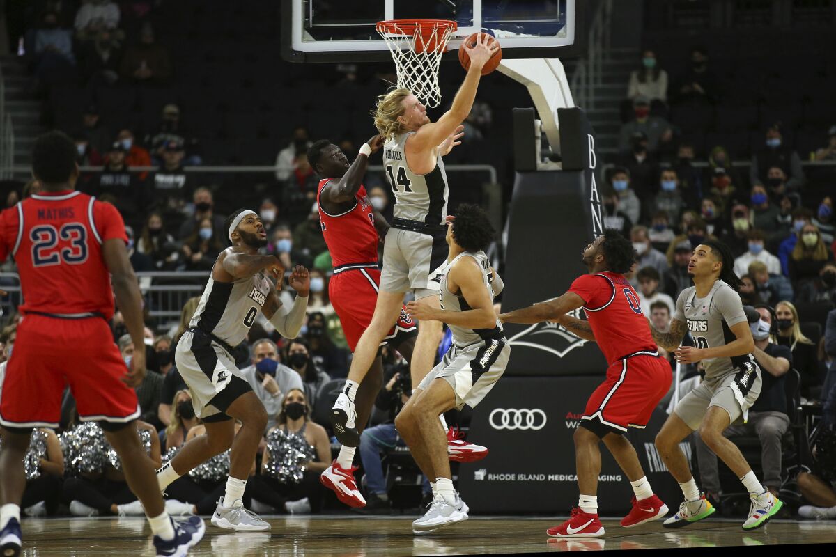 Providence's Noah Horchler (14) grabs a rebound on a shot by St. John's Esahia Nyiwe, third from left, during the first half of an NCAA basketball game on Saturday, Jan. 8, 2022, in Providence, R.I. (AP Photo/Stew Milne)