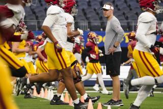 USC coach Lincoln Riley stands on the field and  watches his team warm up around him