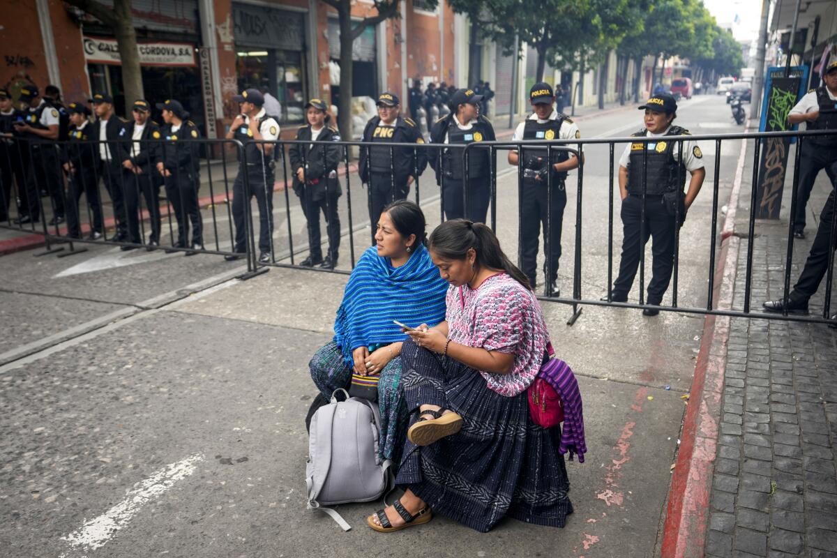Un par de mujeres manifestantes se sientan frente a la policía cerca del edificio del Congreso