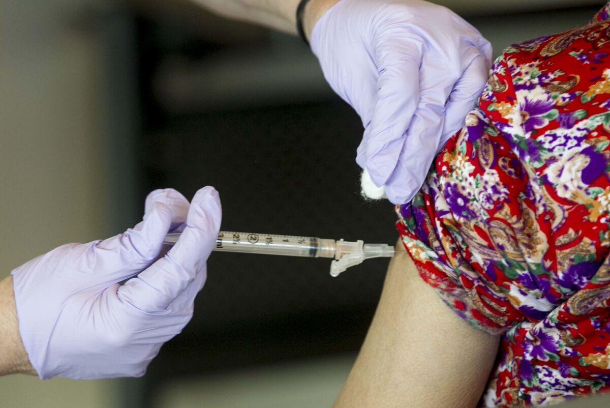 A health care provider administers a flu shot to a woman.